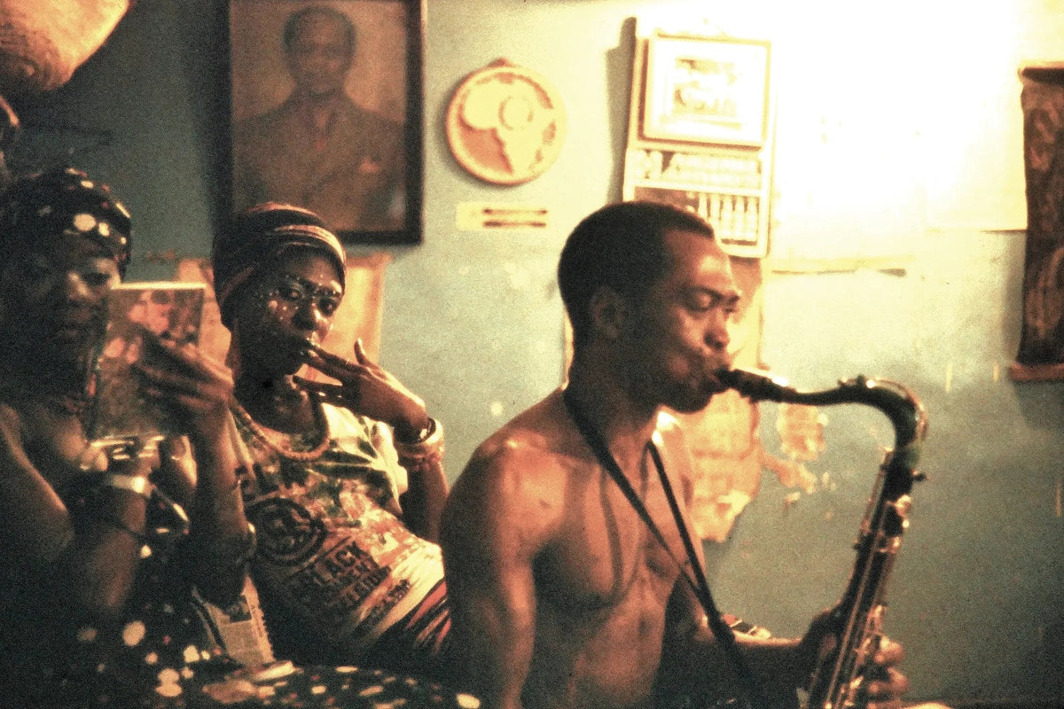 Fela Kuti playing tenor saxophone in the studio with two singers of Africa 70 beside him